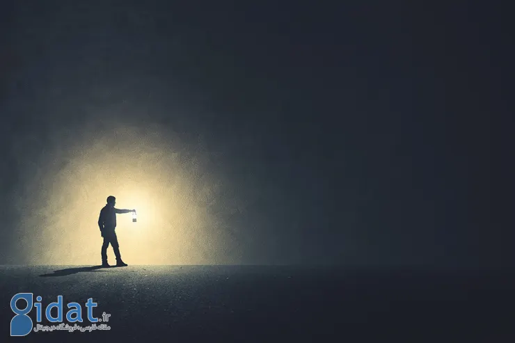 مرد کنار دیوار با چراغ در دست در تاریکی